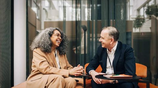 Why attend businesswoman talking with male entrepreneur while sitting on sofa
